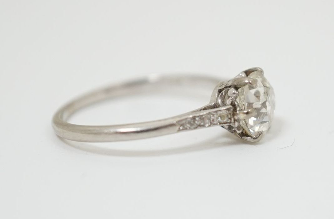 A platinum and single stone diamond ring, with diamond chip set shoulders